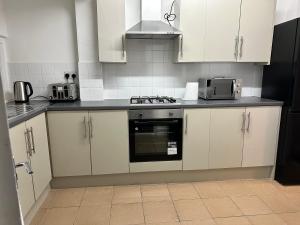 uma cozinha com armários brancos e um forno com placa de fogão em 3 bedroom house with garden in Tottenham london em Londres