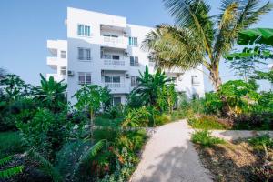 a white building with a palm tree in front of it at Fumbatown Cozy 1 bed Apartment in Fumba