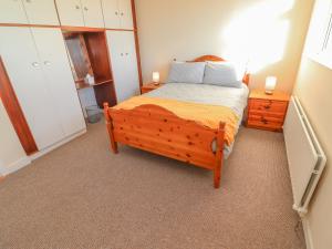 1 dormitorio con 1 cama de madera y 2 mesitas de noche en Mullagh Road, en Miltown Malbay