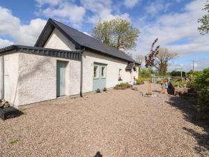 a small white house with a gravel driveway at Lynchpin Cottage in Bruff