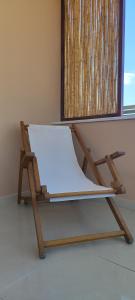 una sedia in legno seduta di fronte a una finestra di Kallistis Beach House a Monolithos