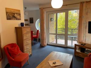 a living room with a red chair and a sliding glass door at Seeblick Wohnung 115 in Ostseebad Koserow