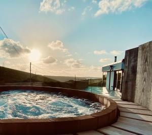 a hot tub on a deck next to a house at Rockpools in Newquay Bay Resort