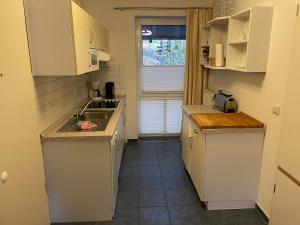奥斯科瑟羅的住宿－Seeblick Wohnung 113 mit teilw Meerblick，小厨房配有白色橱柜和水槽