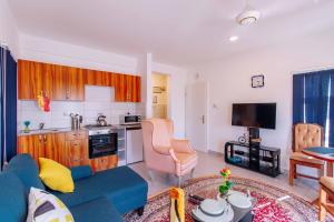 a living room with a blue couch and a kitchen at Fumbatown Cozy 1 bed Apartment in Fumba