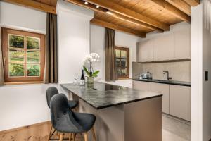 a kitchen with a counter and two chairs at Apartments Perfila Falkenauge in Valdaora