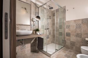 uma casa de banho com uma cabina de duche em vidro e um lavatório. em Hotel Gli Ulivi em Orosei