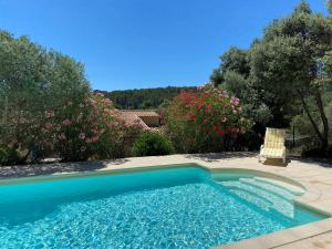 a swimming pool in a yard with a chair and flowers at Mas d'Olea in Lauris