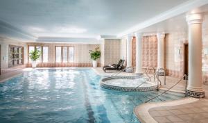 einen Pool mit Whirlpool in einem Zimmer mit Säulen in der Unterkunft New Hall Hotel & Spa, Birmingham in Birmingham