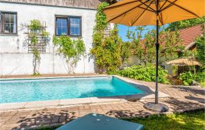a pool with an umbrella next to a house at 1 Bedroom Nice Apartment In Gottsdorf in Gottsdorf