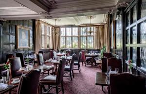 a restaurant with tables and chairs in a room with windows at New Hall Hotel & Spa, Birmingham in Birmingham