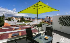 um guarda-sol amarelo numa varanda com uma mesa e cadeiras em Home Azores - Casas da Ladeira em Ponta Delgada
