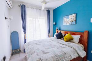 Schlafzimmer mit blauen Wänden und einem Bett mit gelben Kissen in der Unterkunft Fumbatown Cozy 1 bed Apartment in Fumba