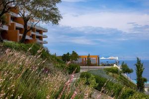 a building on a hill with a view of the ocean at Angsana Corfu Resort & Spa in Benitses