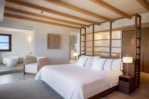 a bedroom with a large white bed and a bathroom at Angsana Corfu Resort & Spa in Benitses
