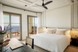 a bedroom with a large white bed and a table at Angsana Corfu Resort & Spa in Benitses