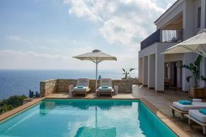 a swimming pool with chairs and an umbrella and the ocean at Angsana Corfu Resort & Spa in Benitses