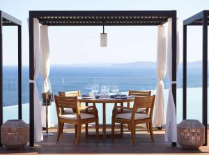 a table with chairs and wine glasses on a balcony at Angsana Corfu Resort & Spa in Benitses