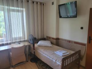 um quarto com uma cama e uma secretária e uma televisão na parede em Albert Turystyczne Usługi Hotelarskie em Varósvia