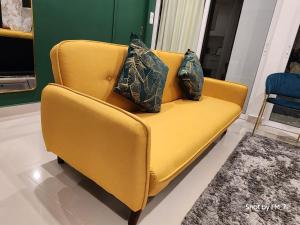 um sofá amarelo com duas almofadas num quarto em Seaview Luxury Suites at The Shore Kota Kinabalu em Kota Kinabalu