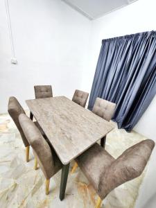 uma sala de jantar com uma mesa de madeira e cadeiras em Happy Vacation Homestay Mersing 2 em Mersing