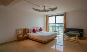 PimpalwandiFabHotel Prime Rester Select - in chakan的一间卧室，有一张带红色枕头的床和一扇窗户