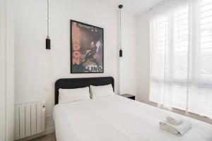 a bedroom with a white bed and a poster on the wall at Bowie House - Madrid River-A-SALVAD in Madrid