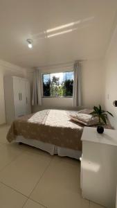 een slaapkamer met een groot bed en een raam bij Casa das Bromélias- Com Quiosque em meio à natureza! in Piratuba