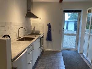 a kitchen with white cabinets and a sink and a window at Ørbakke - Søborg Sø in Græsted