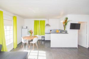 una cucina e una sala da pranzo con tavolo e tende gialle di La Santa Clara - Studio climatisé a Saint-Pierre