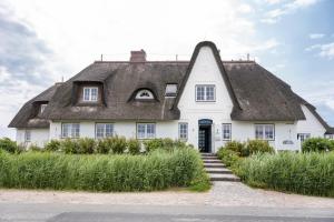 Cette grande maison blanche est dotée d'un toit de chaume. dans l'établissement Strandvogtei Sylt, à Rantum