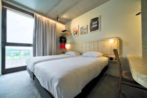 ein Schlafzimmer mit einem großen Bett und einem Fenster in der Unterkunft greet hotel Cernay Mulhouse in Cernay