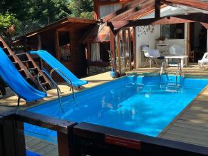 una piscina con un tobogán azul en una casa en BOG Costa de Rio - Piscina climatizada y costa de rio en Villa La Angostura