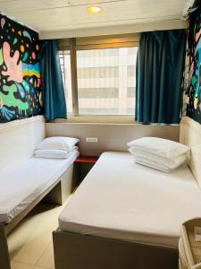 twee bedden in een kleine kamer met een raam bij 嘉應賓館HAKKAS GUEST House in Hong Kong