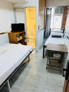 a room with two beds and a table and a bathroom at 嘉應賓館HAKKAS GUEST House in Hong Kong