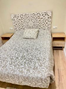 uma cama com um edredão branco e duas mesas de cabeceira em Soleado em Gijón