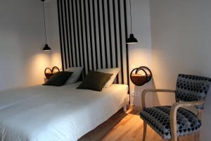 a bedroom with a white bed and a chair at La Maison d'Emile- le Gîte- La Clef de la Grange in La Fouillade +24 photos