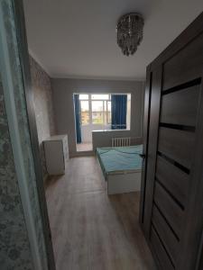 um pequeno quarto com uma cama e uma janela em 2к.апартаменты.7 мкр. em Bishkek
