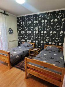 two beds in a bedroom with a black and white wallpaper at Nature Guest House Sarajevo in Sarajevo