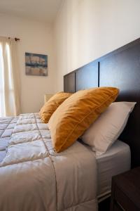 Una cama con almohadas de oro encima. en SANTA GENOVEVA 1 DORMITORIO con EXCELENTES VISTAS A LA CIUDAD DE NEUQUEN en Neuquén
