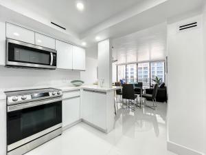 a kitchen with white cabinets and a table with chairs at Beach Paradise a cozy ocean view condo on the beach with free parking in Hollywood