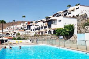 a swimming pool in front of some apartment buildings at Stylish bungalow with sea views in Mogán