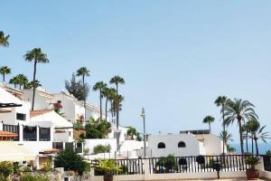 a row of white houses with palm trees in the background at Stylish bungalow with sea views in Mogán