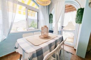 a dining room with a table and chairs and windows at Stylish bungalow with sea views in Mogán