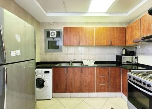 a kitchen with wooden cabinets and a washer and dryer at RH- Exquisite & Spacious 01 BR, Near Mall of the Emirates in Dubai