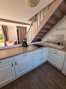 a kitchen with white cabinets and a staircase at Maison Huchet à 10min du parc le Puy duFou in Mallièvre