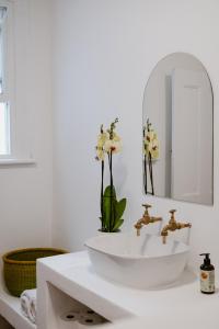 een witte badkamer met een wastafel en een spiegel bij Bonne Esperance, Simon's Town in Simonʼs Town
