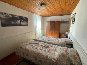 a bedroom with two beds and a wooden ceiling at Maison Lavande in Blismes