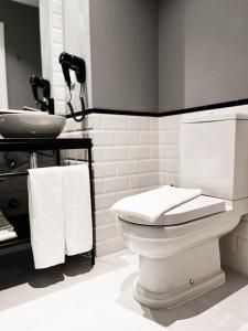 La salle de bains est pourvue de toilettes blanches et d'un lavabo. dans l'établissement GRANDE HOTEL PARIS by STAY HOTELS, à Porto