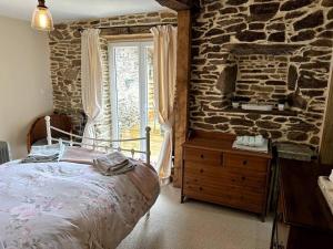 een slaapkamer met een bed en een stenen muur bij "L'Annexe" in Dournazac